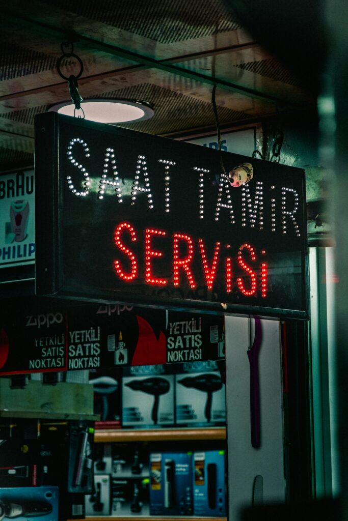 LED sign for watch repair service in urban store at night.